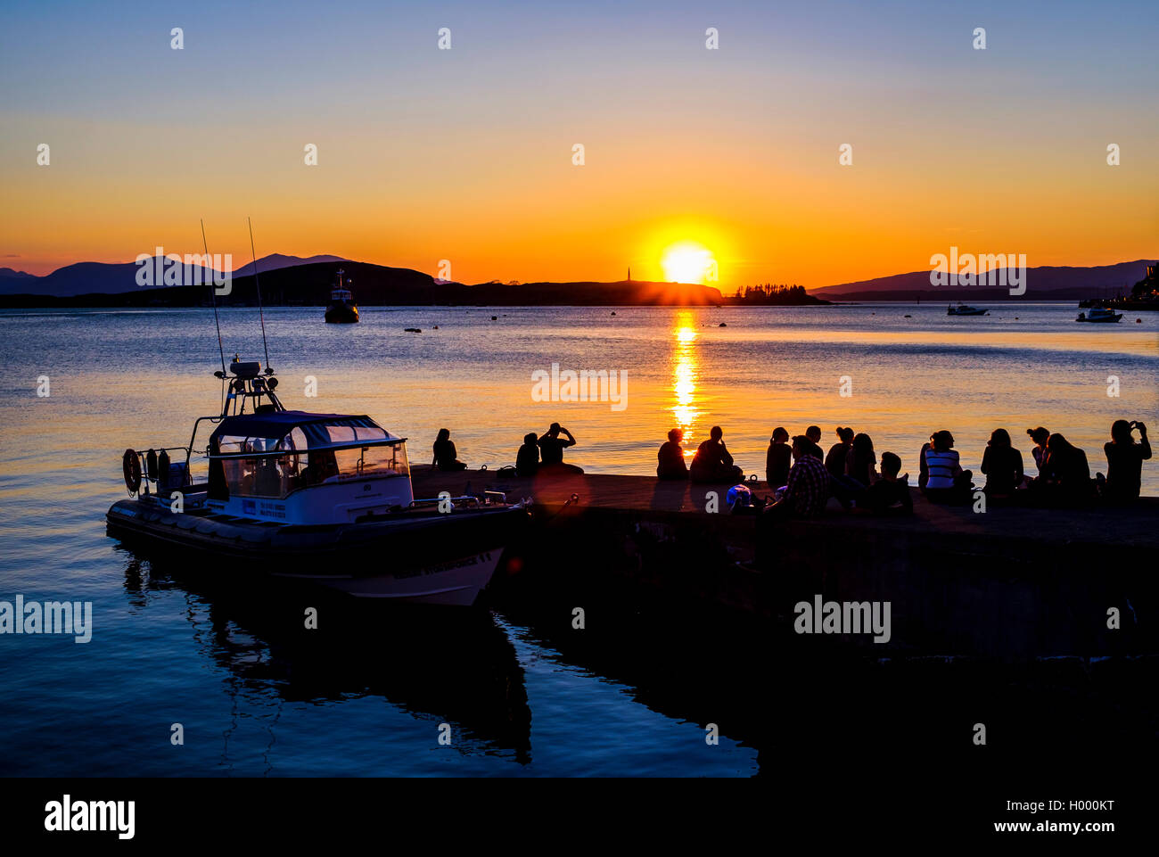 Silhouette of young people in the water, watching the sunset, Oban, Argyll and Bute, Scotland, United Kingdom Stock Photo