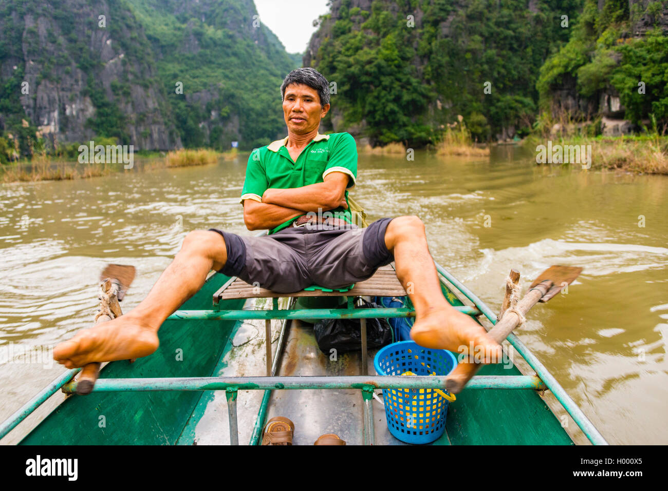 Local man rowing with his feet on the Ngo Dong River, Song Ngô Dong, Tam Coc, Ninh Binh, Vietnam Stock Photo