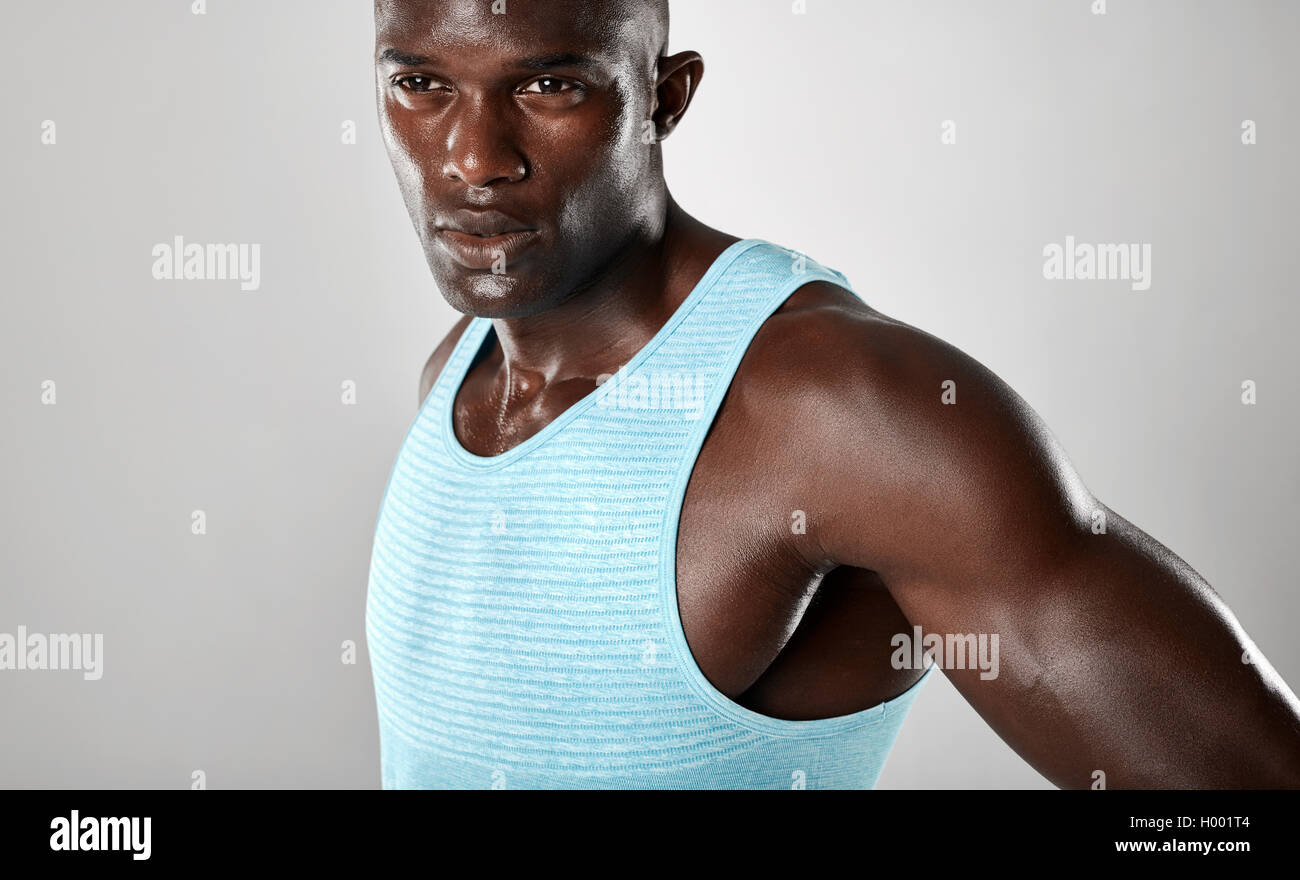 Close up shot of confident young african man with muscular build looking away over grey background. Stock Photo