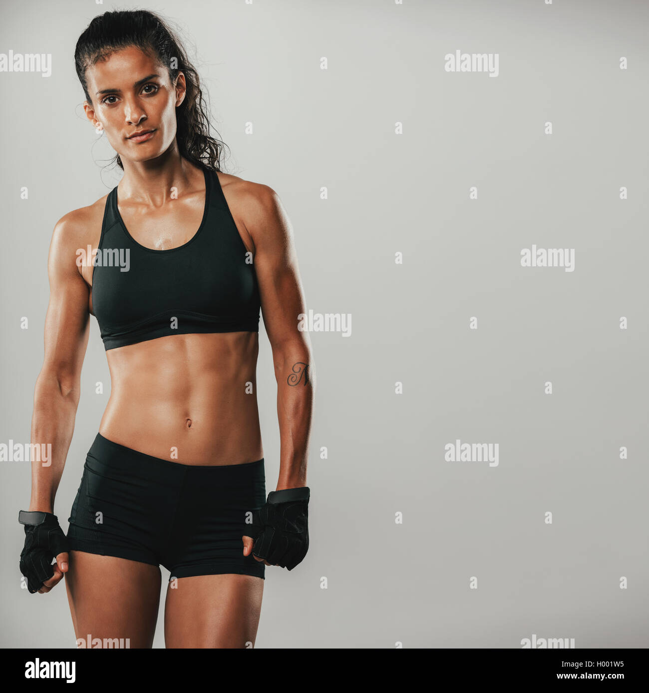 Attractive strong healthy woman in sportswear posing looking at the camera with a serious expression in a fitness and exercise c Stock Photo