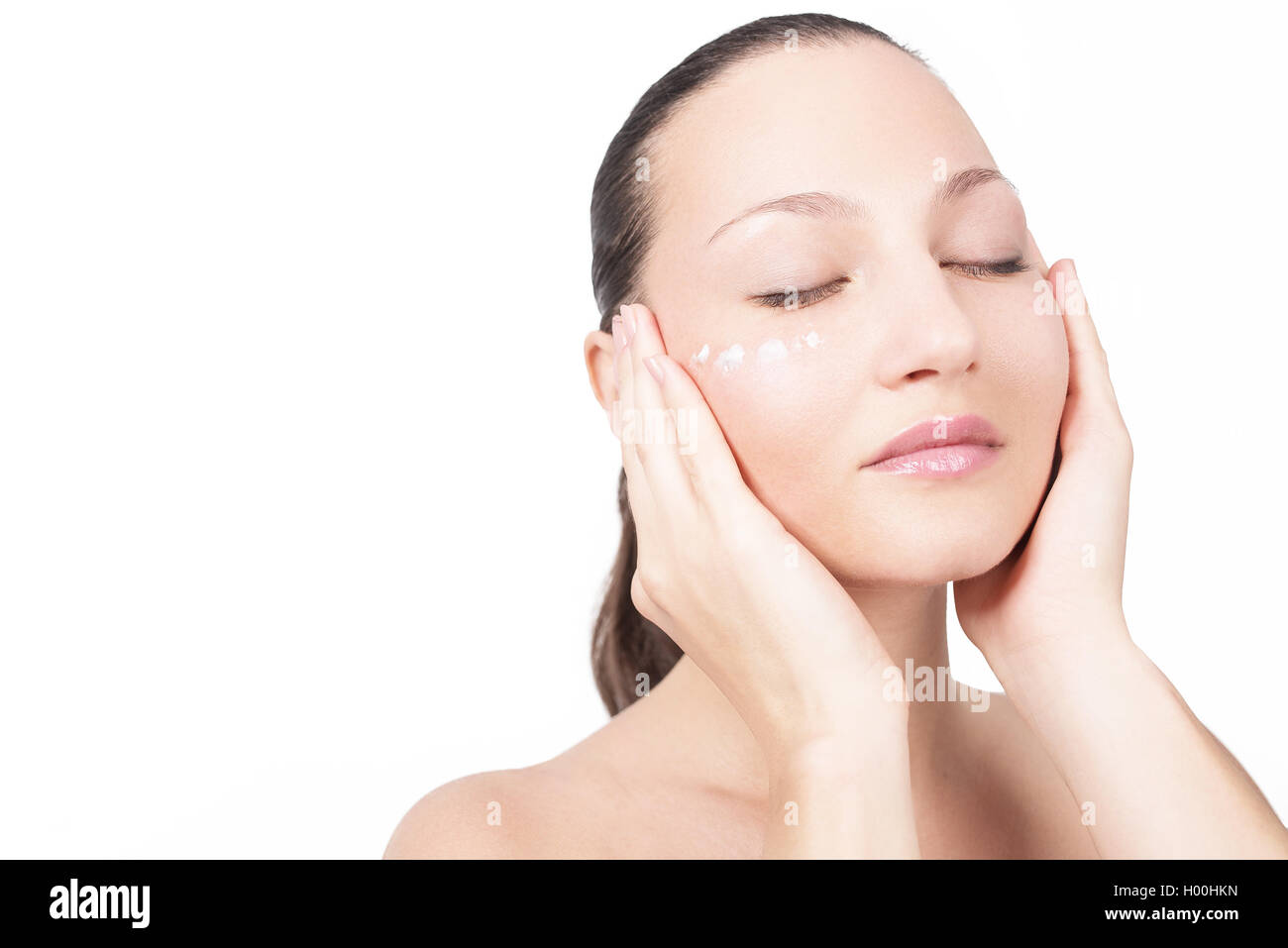Close-up young beautiful face of girl applying moisturize cream - isolated Stock Photo