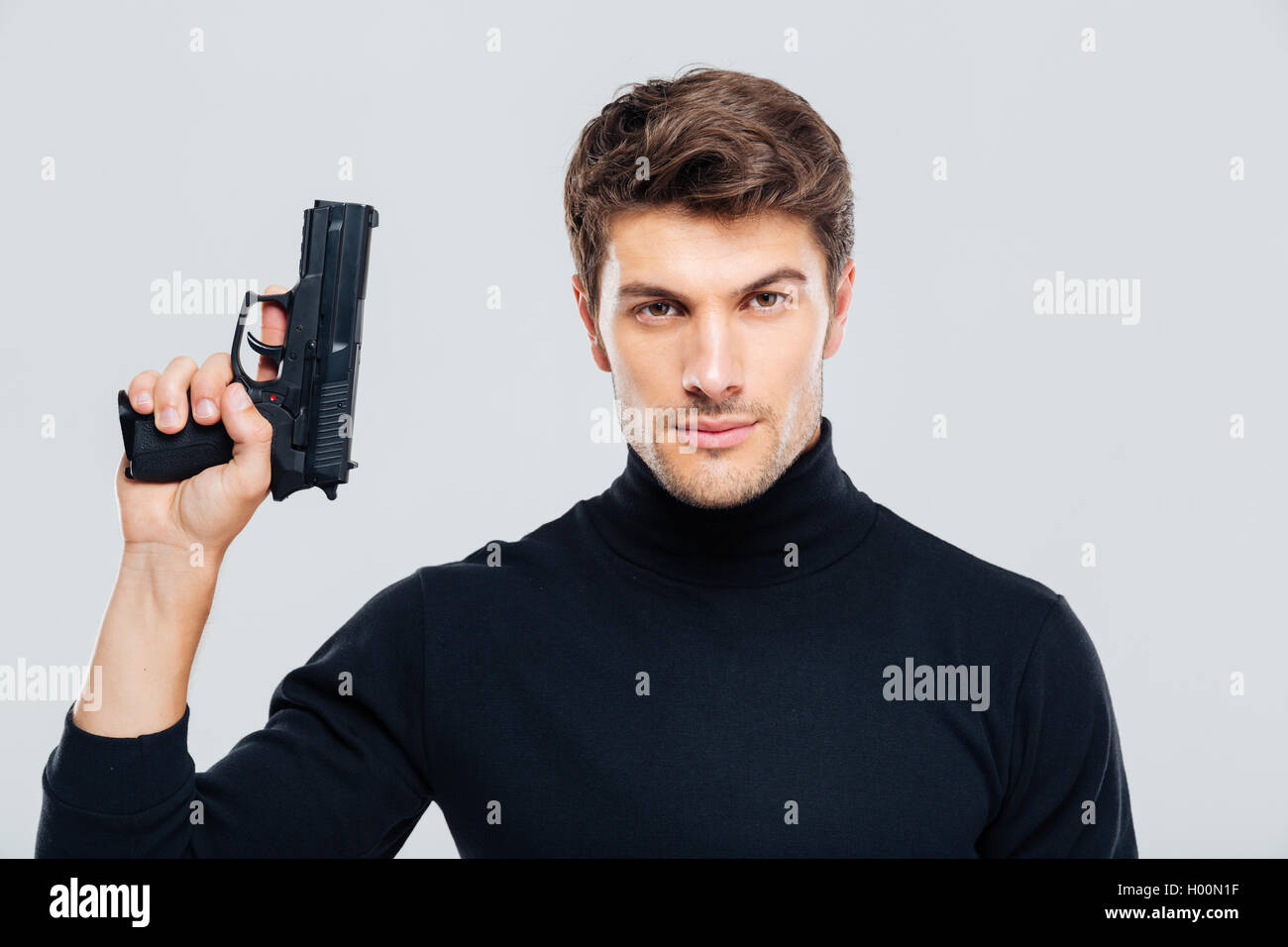 Portrait of handsome young man holding a gun Stock Photo