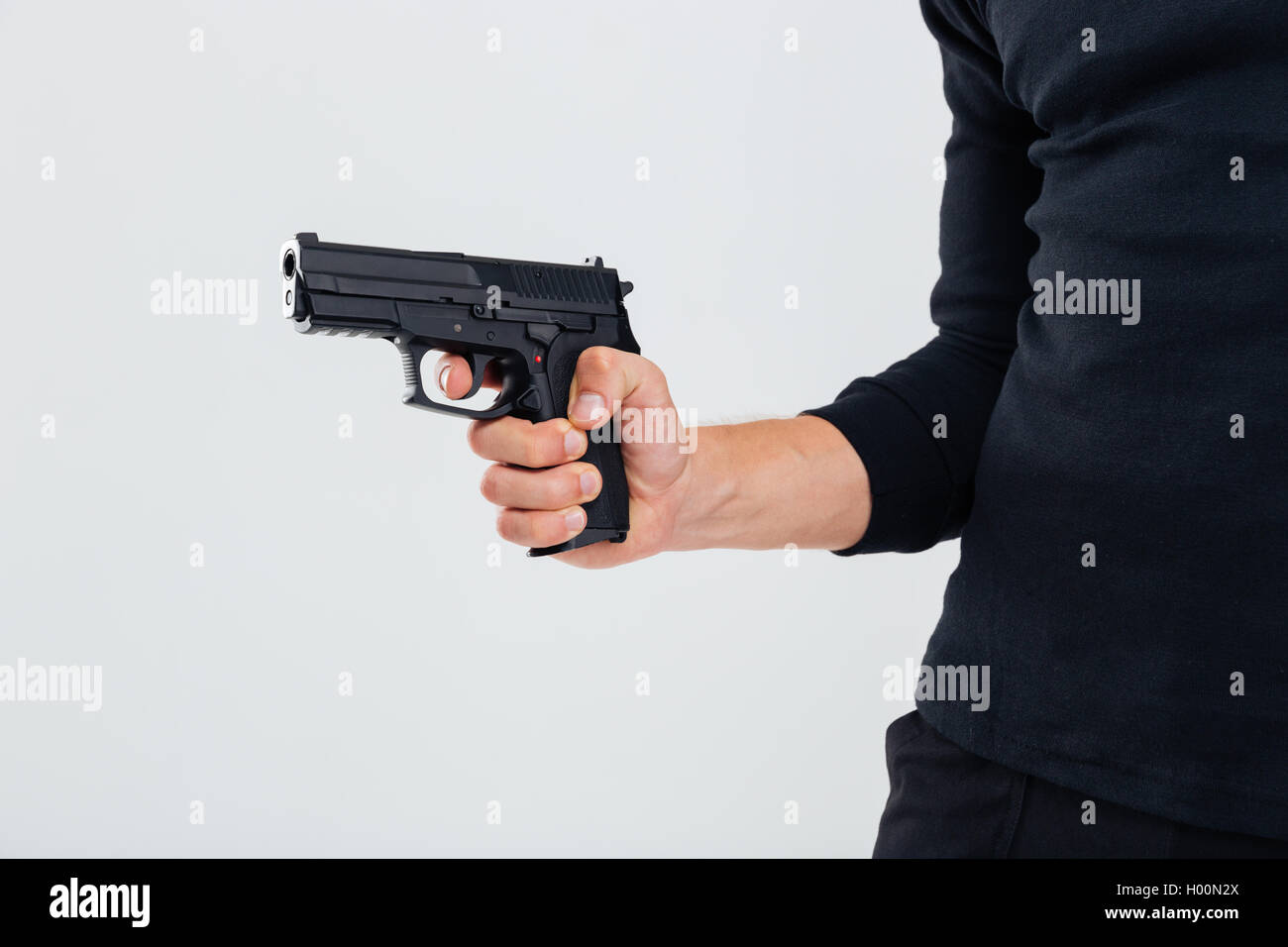 Closeup of man in black clothes holding a gun Stock Photo