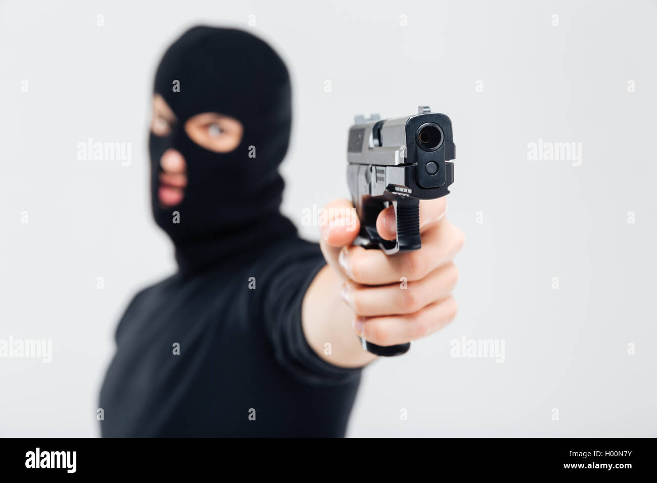 Man robber in balaclava pointing with gun Stock Photo