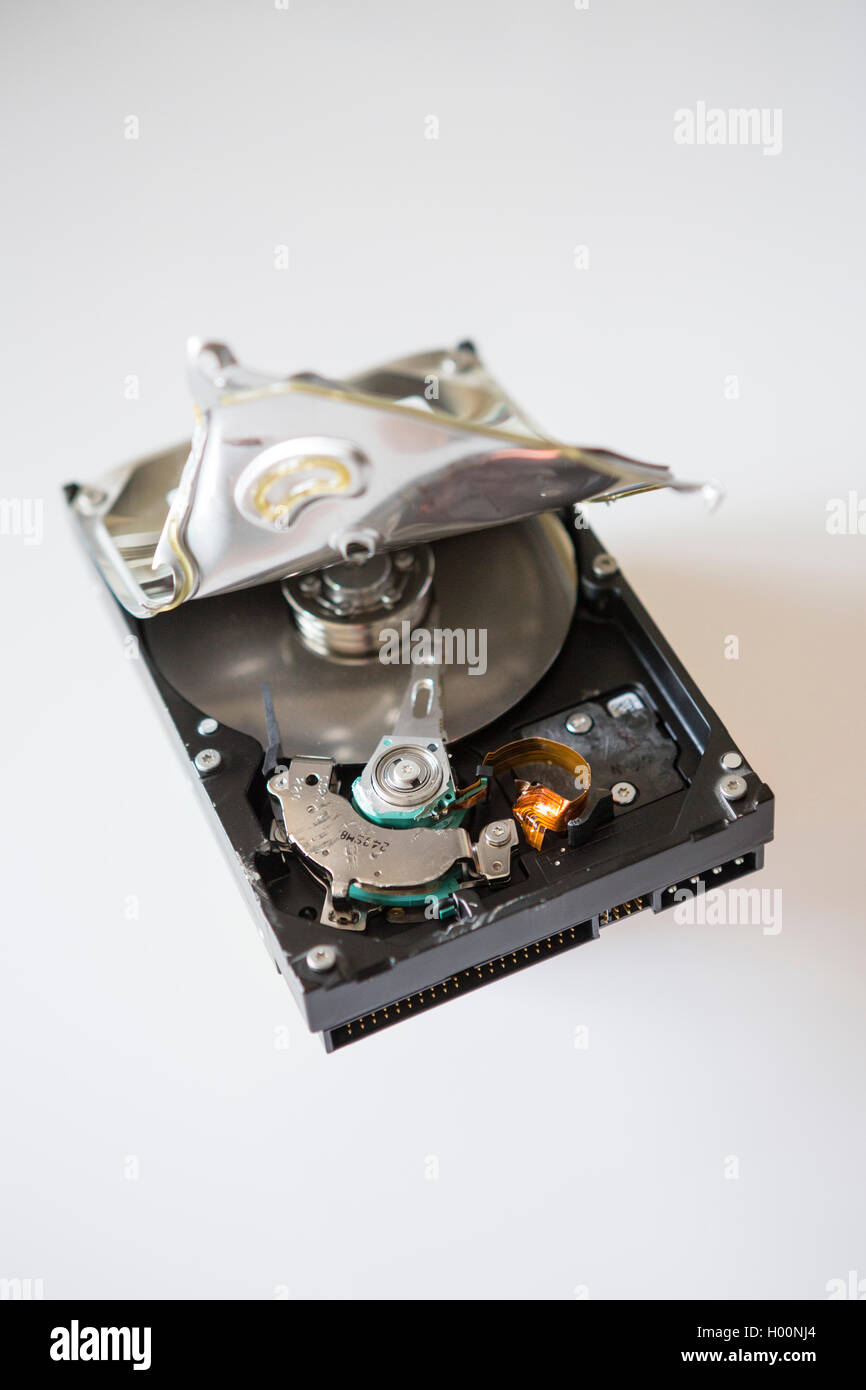 A broken computer hard drive with casing cracked open and disc visible