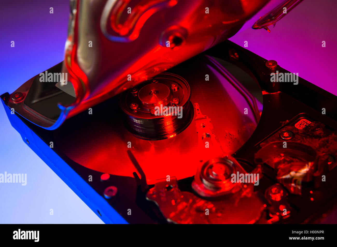 A broken computer hard drive with casing cracked open and disc visible