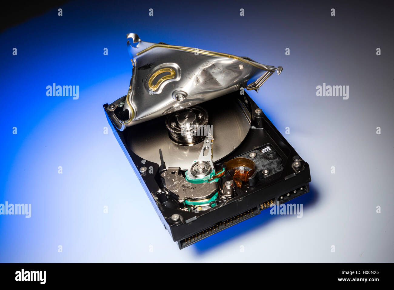 A broken computer hard drive with casing cracked open and disc visible