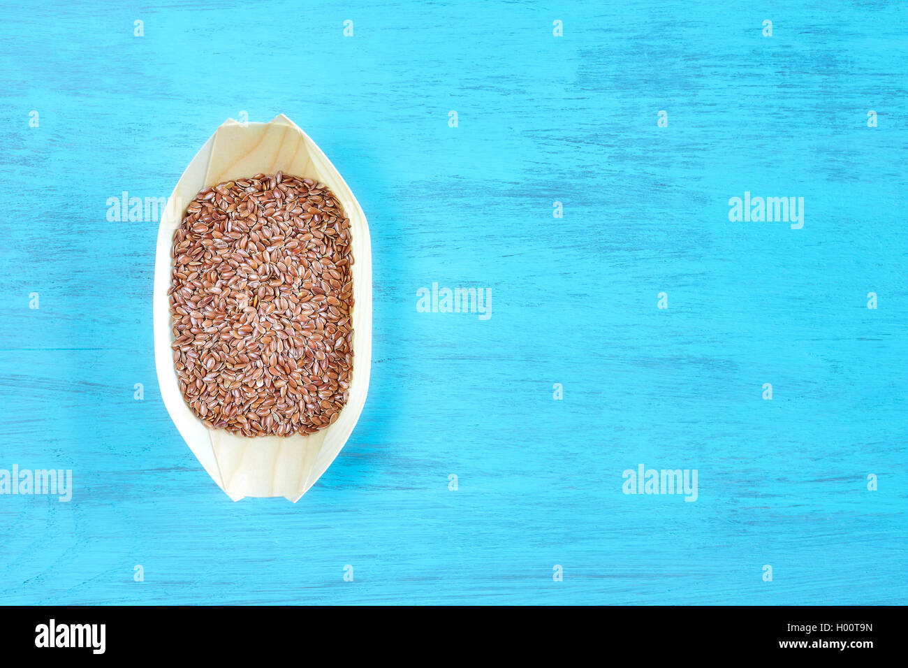 Flax seeds in a wooden bowl on rustic table, space for text, top view. Stock Photo