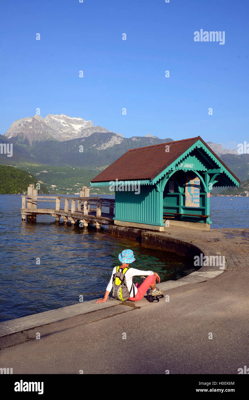 woman sitting at a landing stage and wooden hut at Lake Annecy, France, Haute-Savoie, Saint-Jorioz Stock Photo
