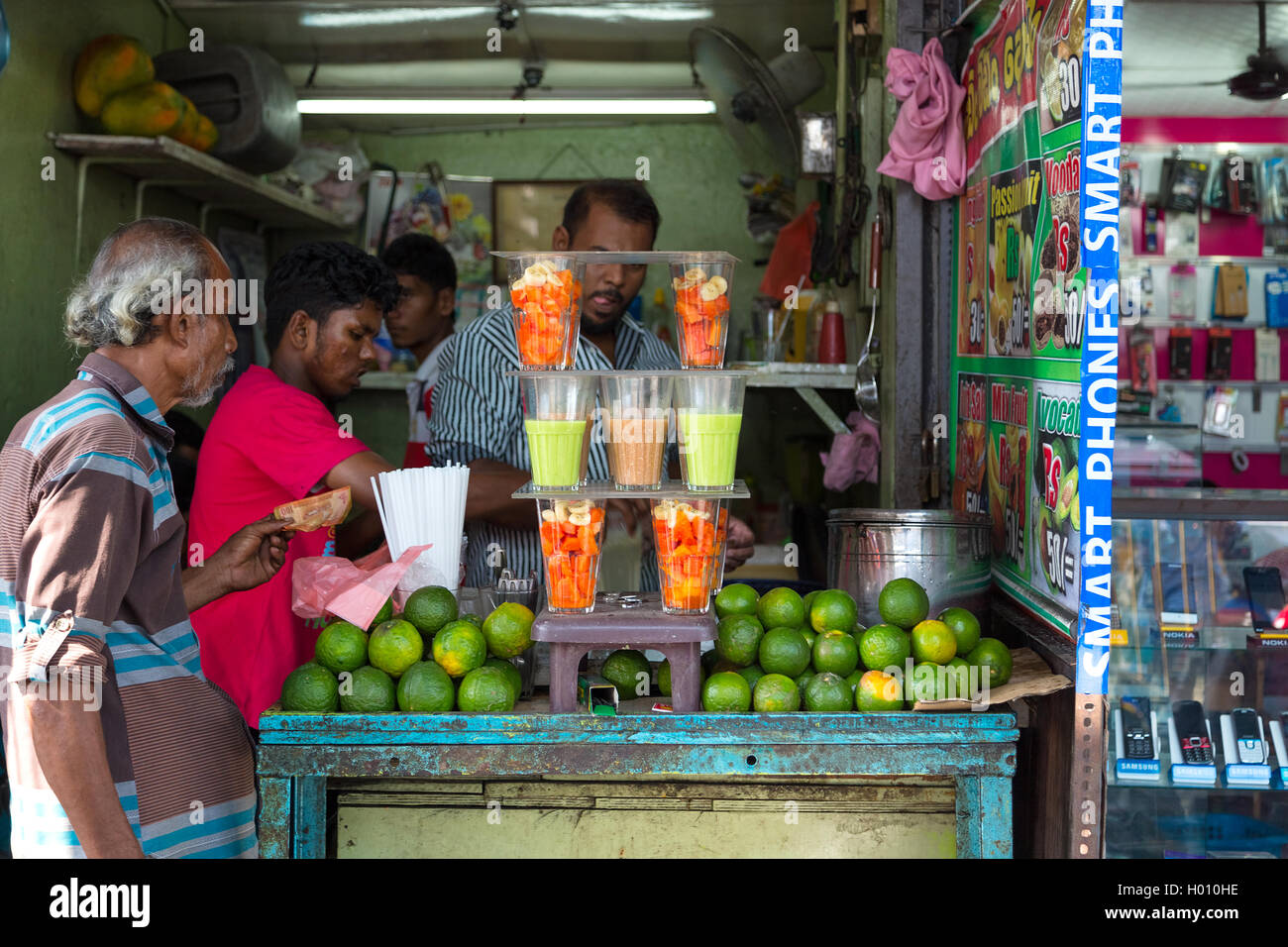 COLOMBO, SRI LANKA - FEBRUARY 22, 2014: Local man buying fruit juice from one of many street vendor in the city. Stock Photo