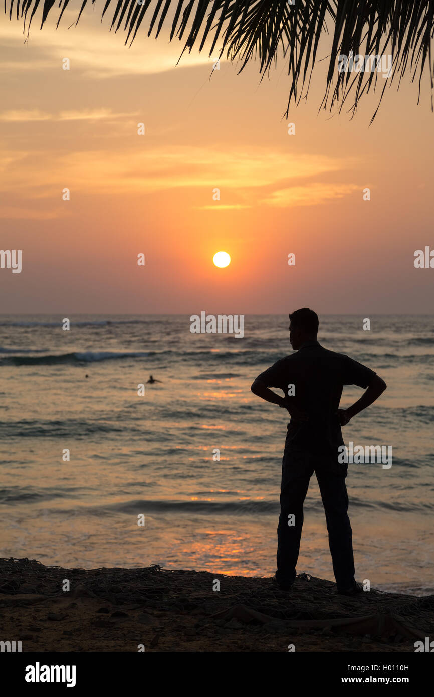 Silhouette of a man standing on sandy beach at sunset Stock Photo - Alamy