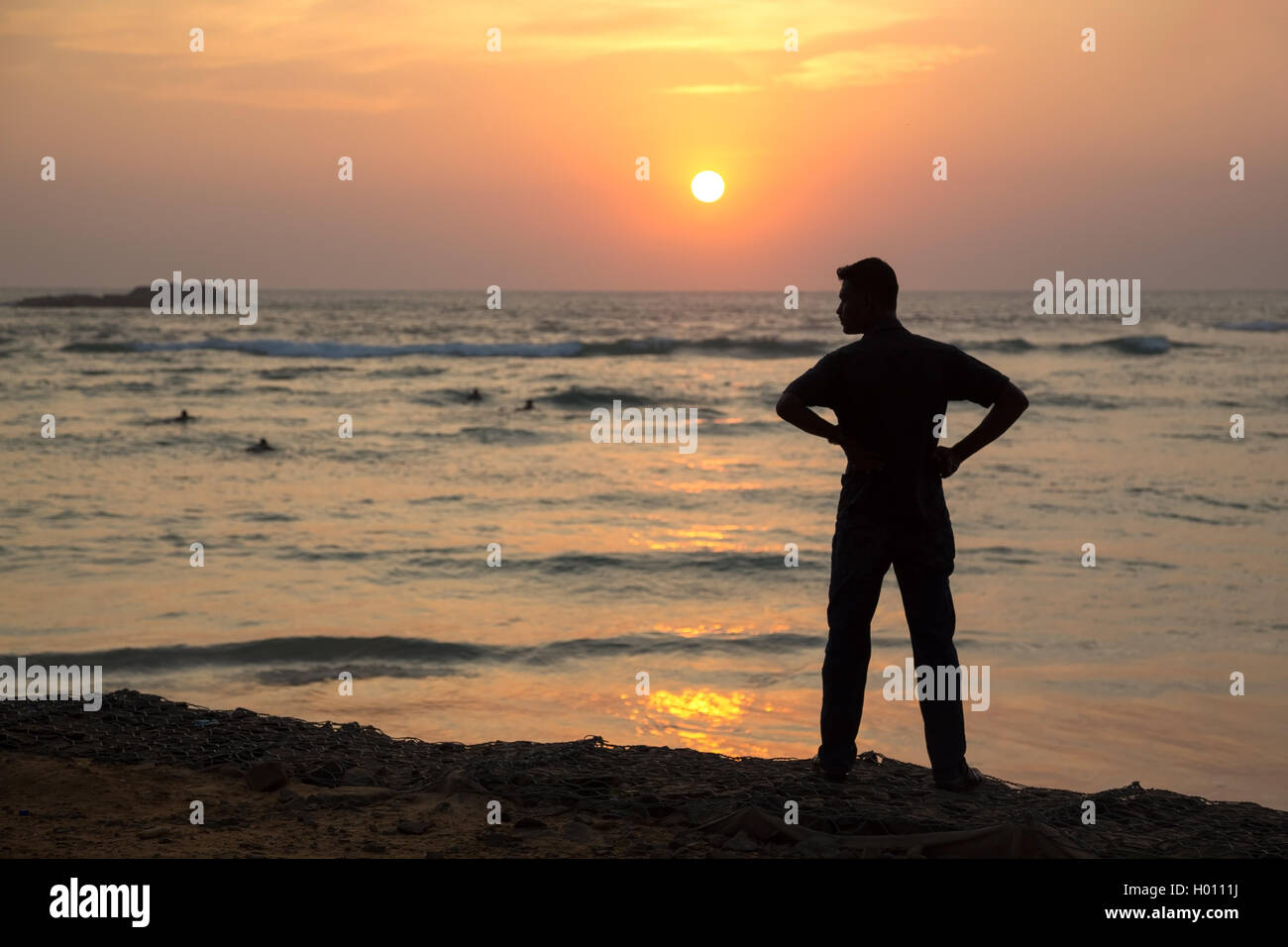 Silhouette of a man standing on sandy beach at sunset Stock Photo - Alamy