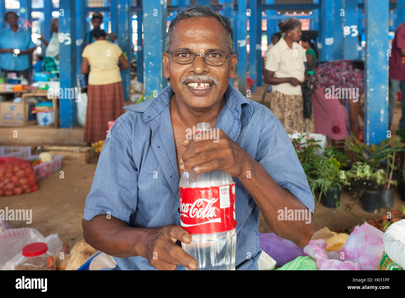 HIKKADUWA, SRI LANKA - FEBRUARY 23, 2014: Portrait of local street vendor with water bottle. The Sunday market is great way to s Stock Photo