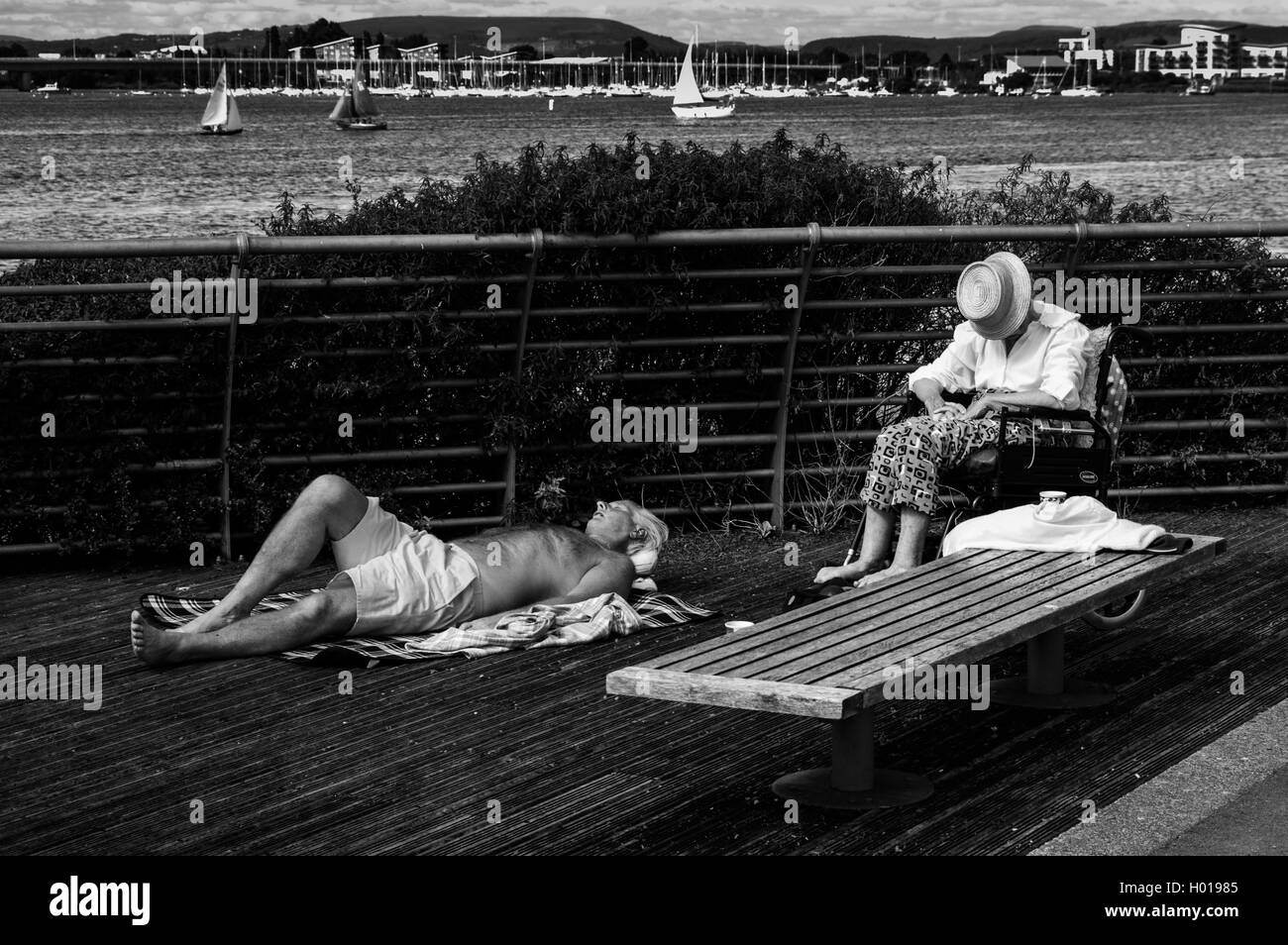 An image taken down Cardiff Bay showing an elderly man and lady sun bathing along the barrage. Stock Photo