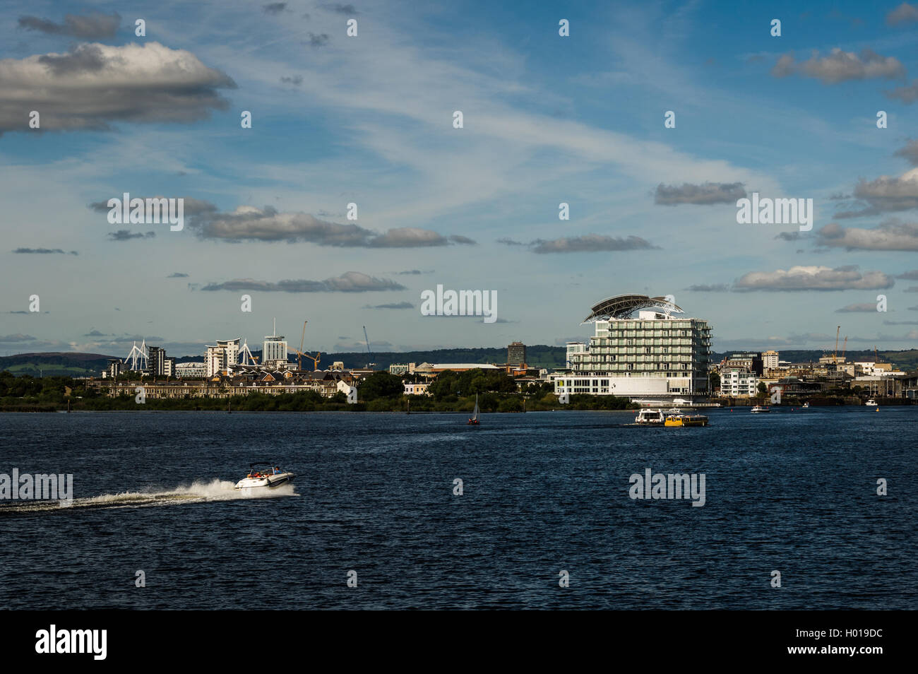 A wide shot of Cardiff Bay from the barrage showing St. Davids Hotel as well as a speeding boat sailing on the water Stock Photo