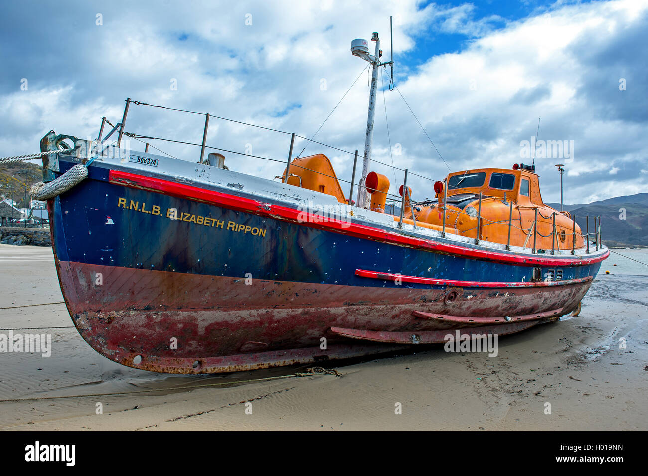 An old retired lifeboat lies beached in Barmouth harbour Stock Photo