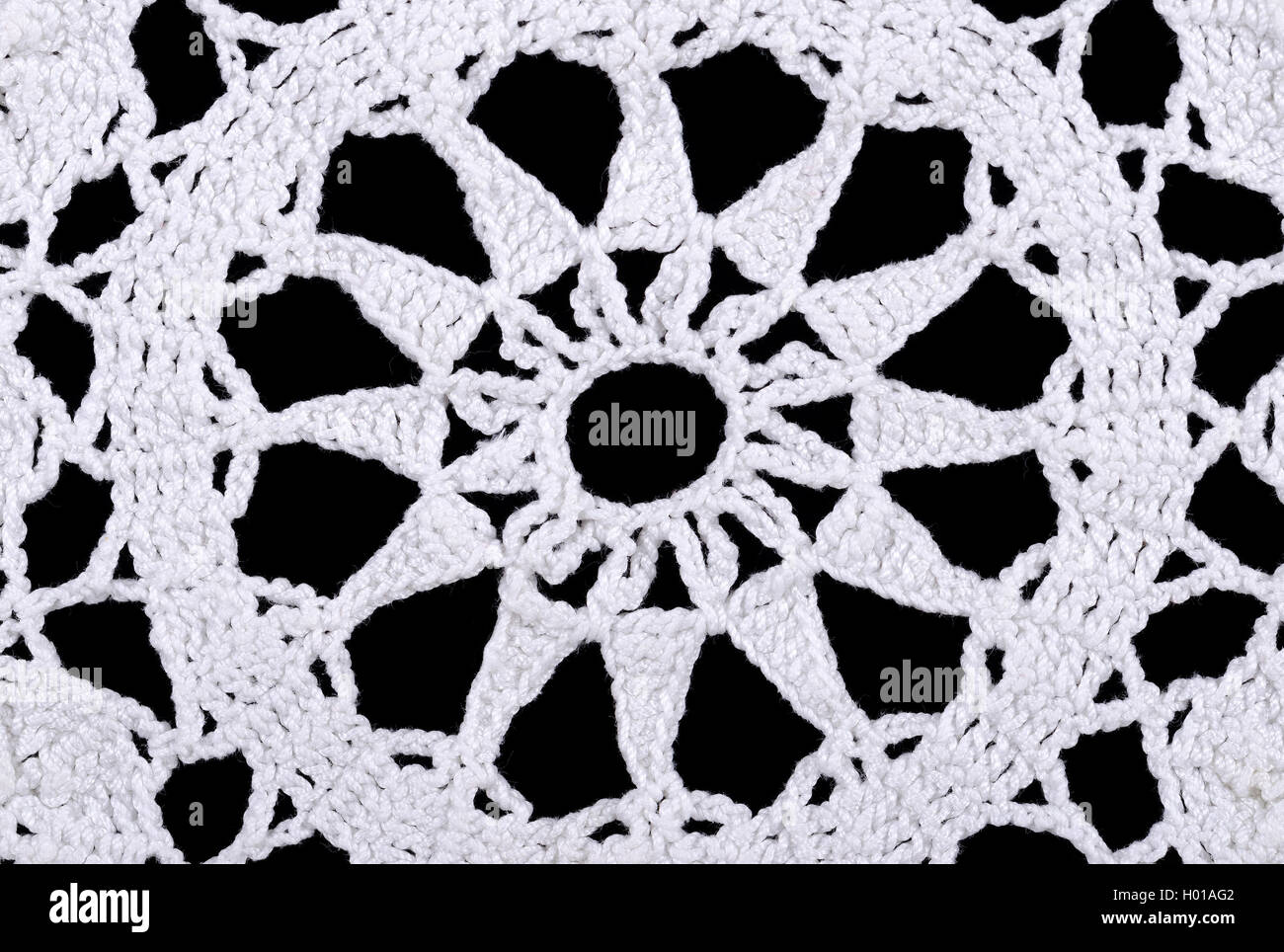 Star in a white crocheted doily. Crochet is a process of creating fabric by interlocking loops of yarn  using a crochet hook. Stock Photo