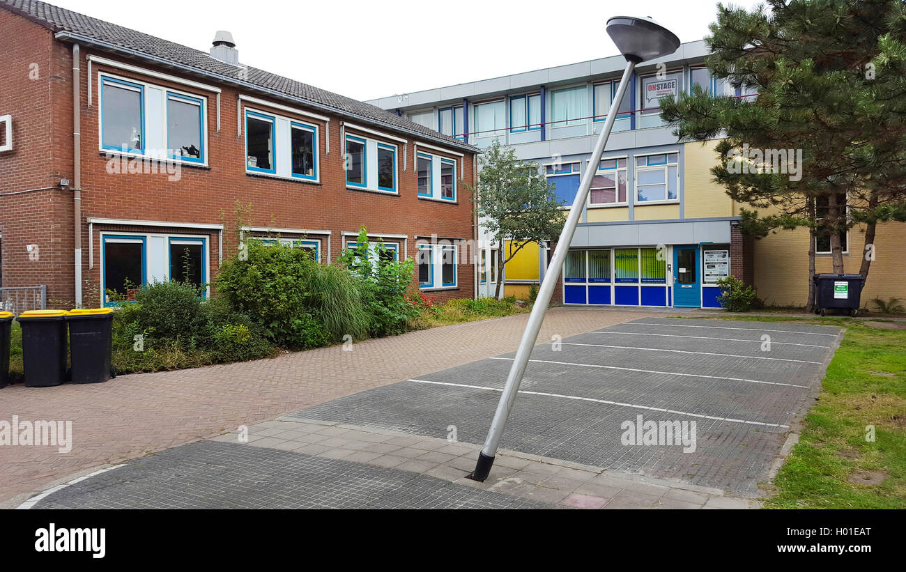 knocked down street lamp on a parking place in front of a school building, Netherlands Stock Photo