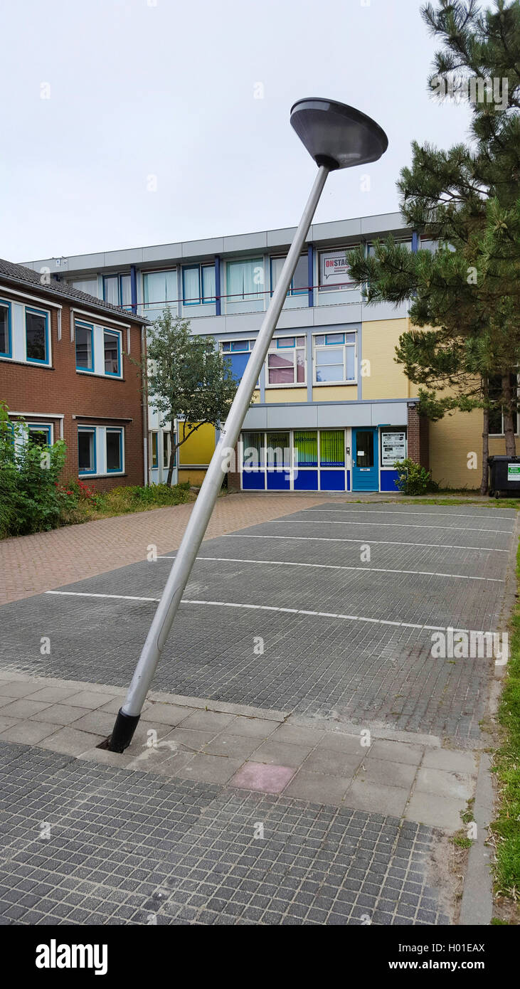 knocked down street lamp on a parking place in front of a school building, Netherlands Stock Photo