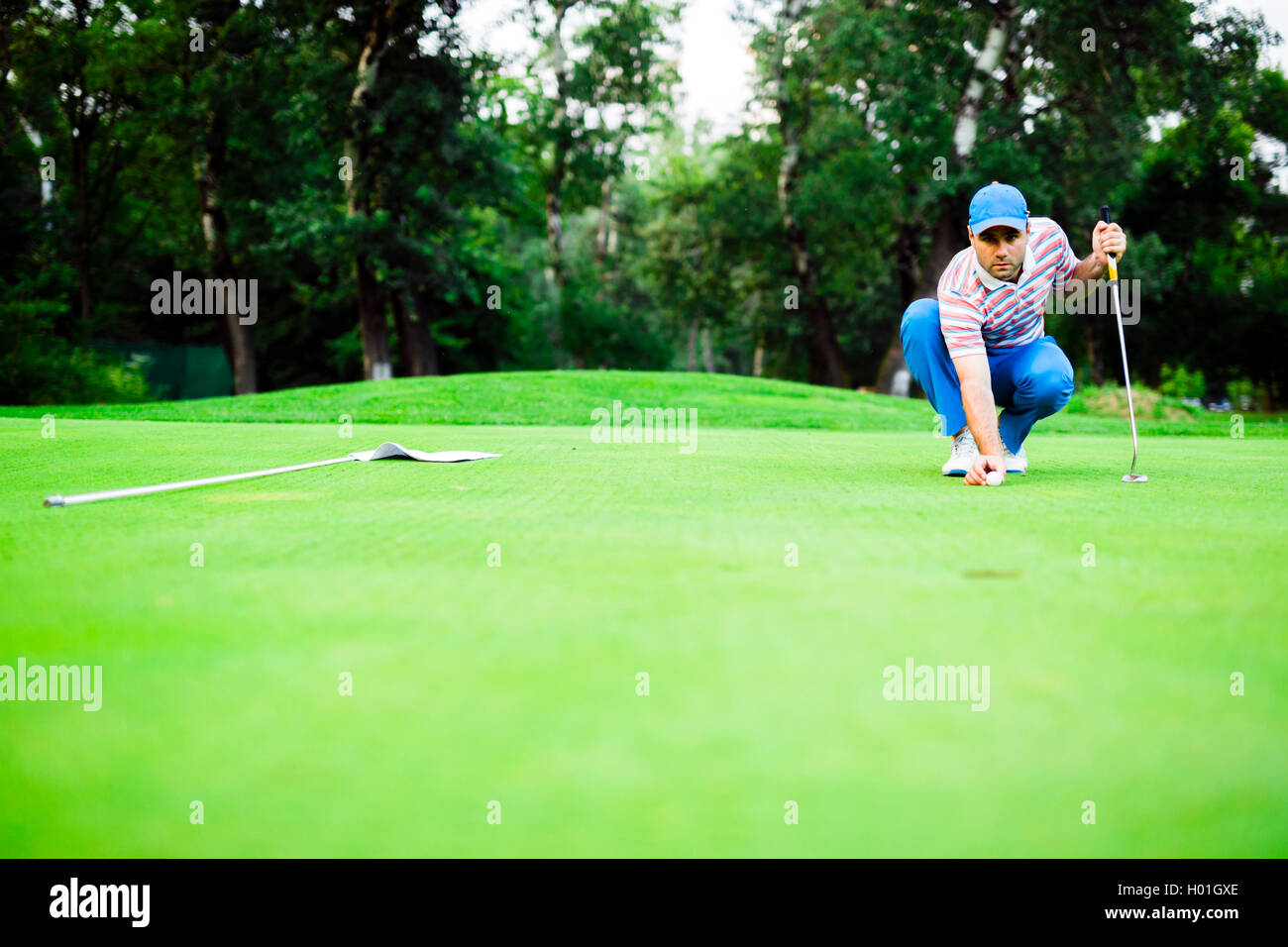 Golf player marking ball on the putting green before lifting the ball
