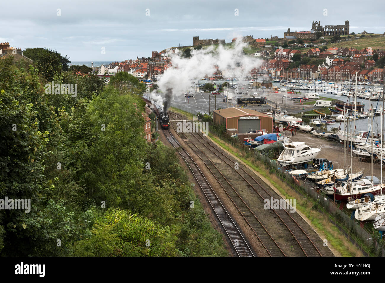 Whitby. A North Yorkshire Moors Railway steam train passes the harbour, with the abbey and the St Mary's Church on the horizon. Stock Photo