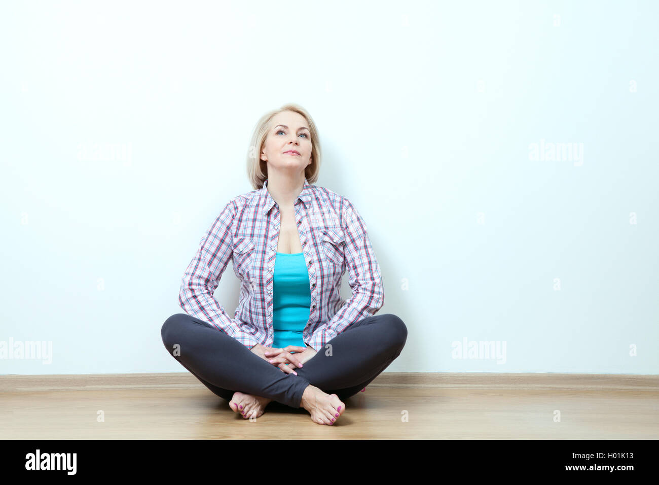 Woman sitting relaxed on the floor near a white wall Stock Photo - Alamy