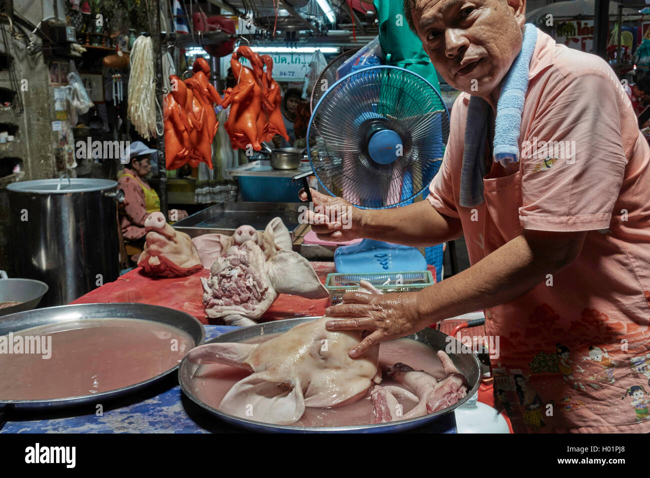 Thailand butcher shaving the face and head of a pig to be more presentable for sale on his market stall. Thailand S. E. Asia Stock Photo