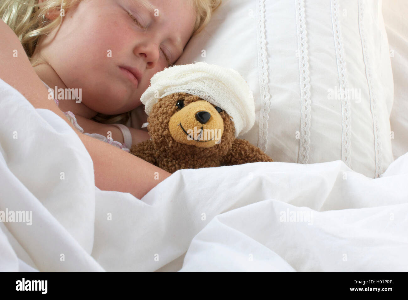 A young girl poorly in bed cuddling her teddy who also feels poorly Stock Photo Alamy