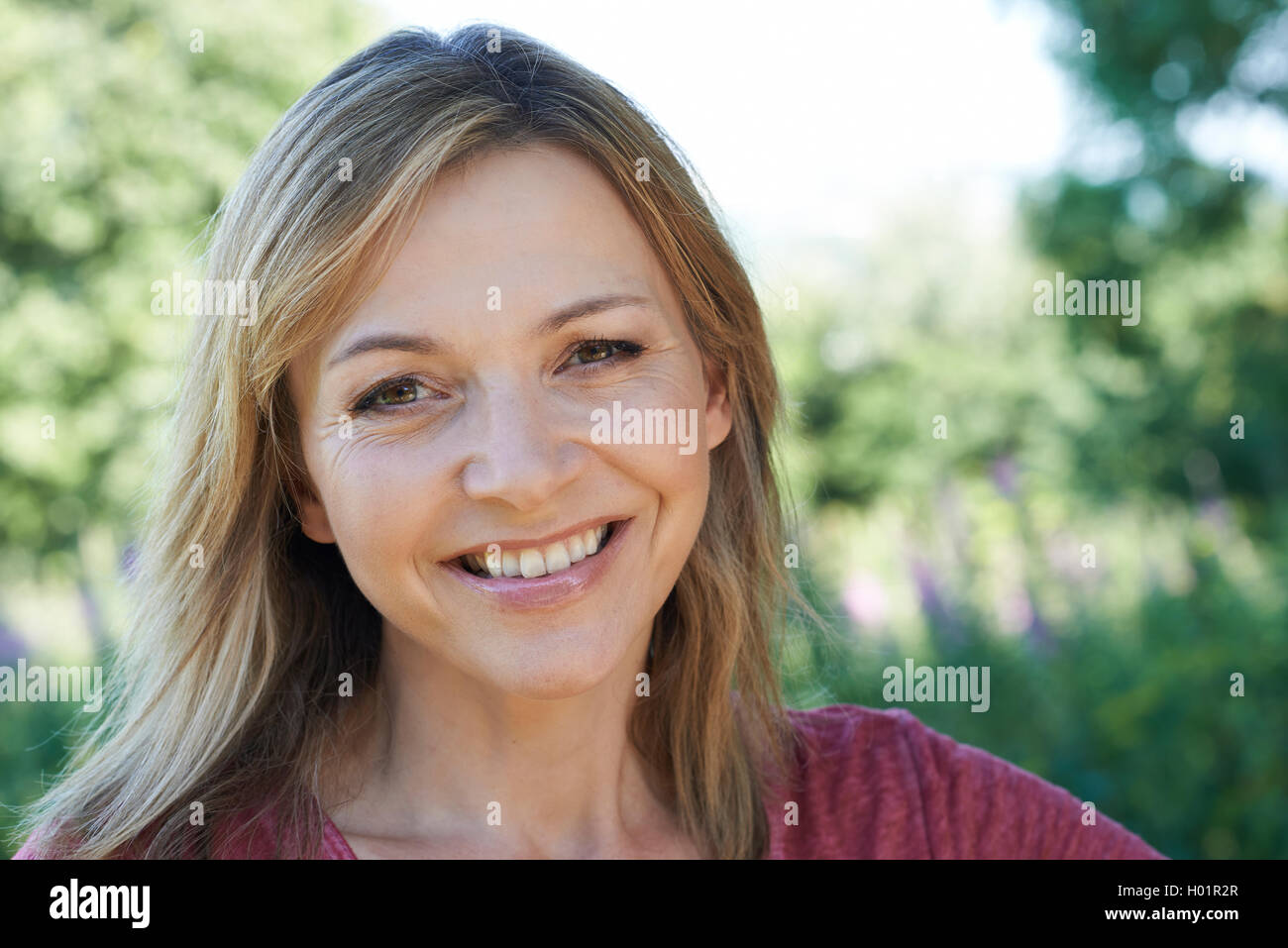 Outdoor Head And Shoulders Portrait Of Smiling Mature Woman Stock Photo