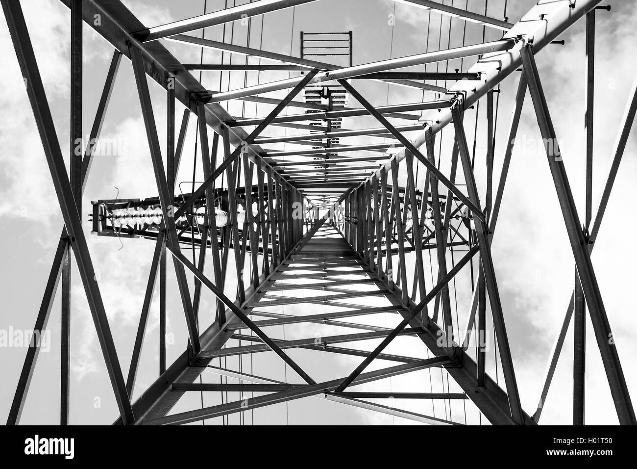 Lattice-type steel tower as a part of high-voltage line. Photo from below with perspective effect. Overhead power line details Stock Photo