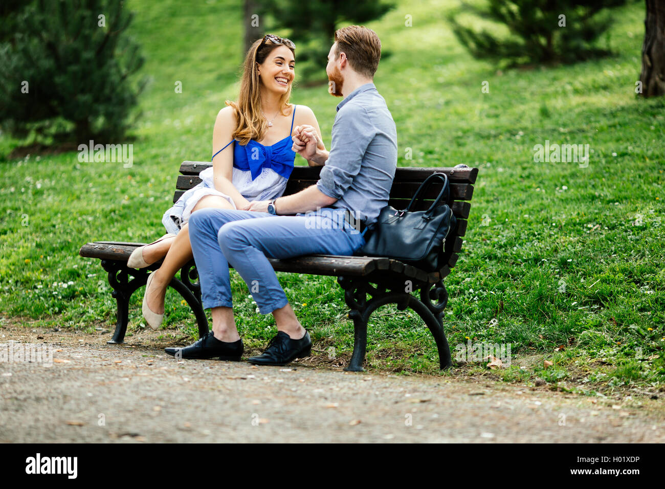 Romantic couple in park sitting on bench Stock Photo - Alamy