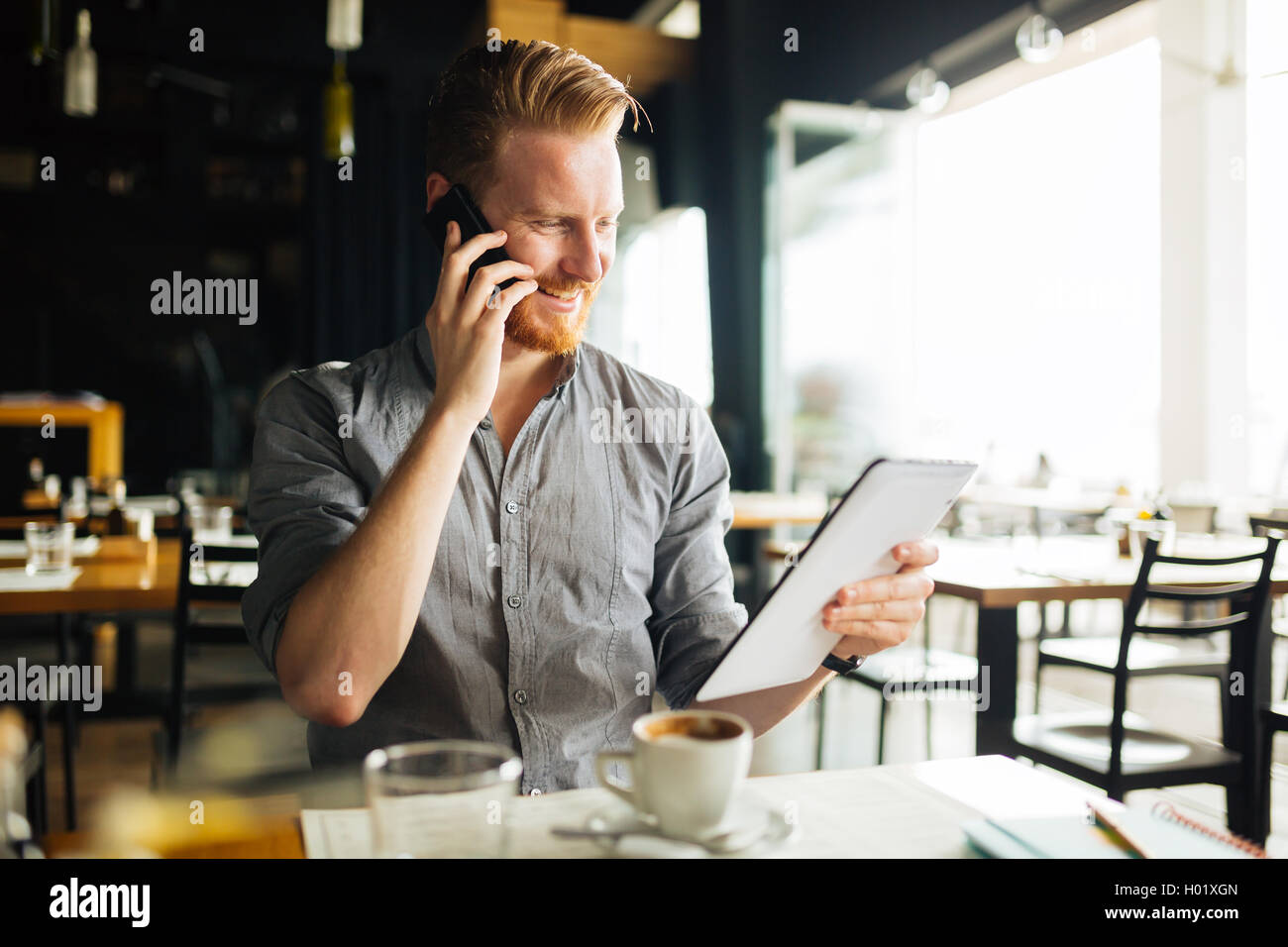 Busy blogger multitasking in cafe Stock Photo