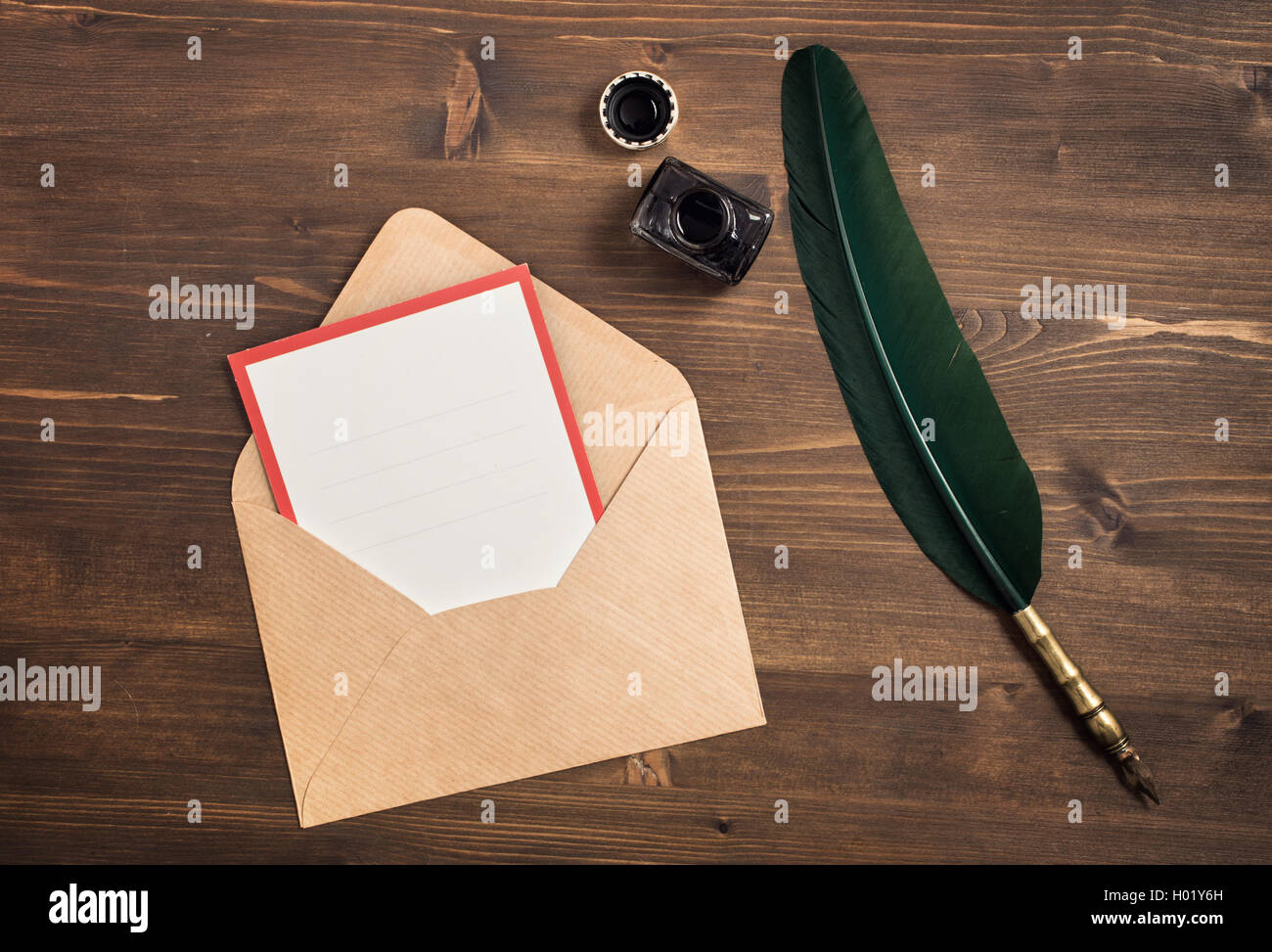 Envelope with empty card and quill pen on wooden table Stock Photo