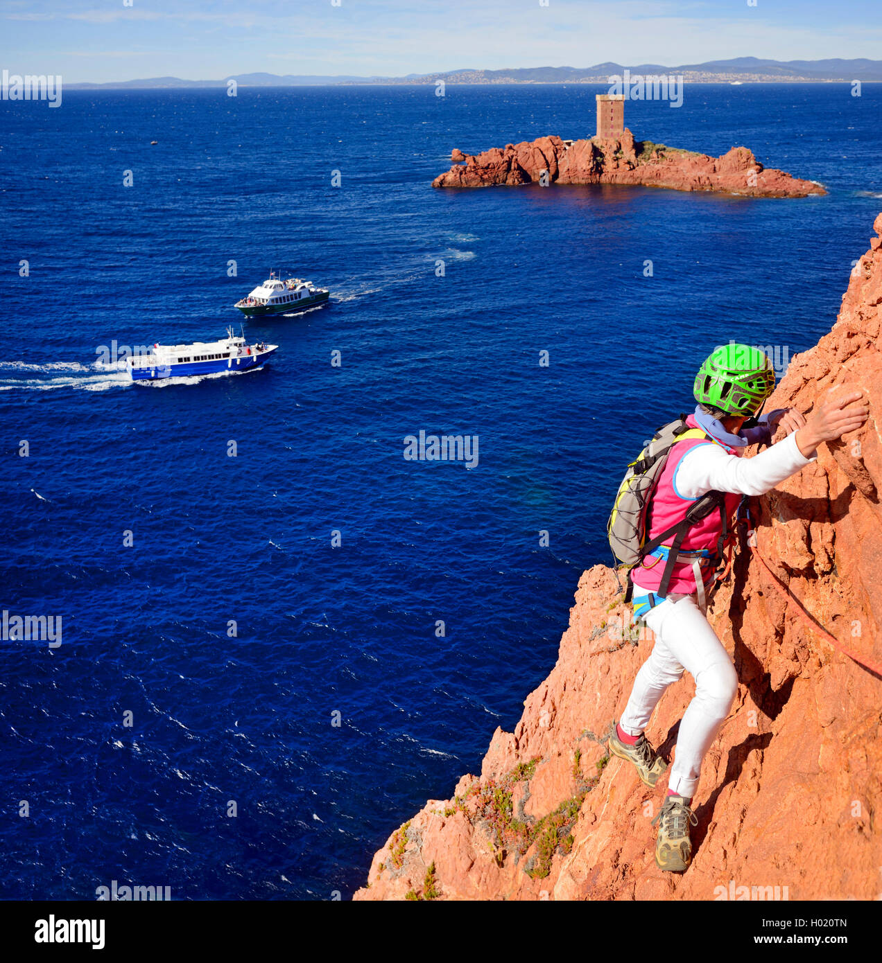 climber at rocky coast of Esterel massif, tower on ╬le dÆOr in background, France, Cotes D. Azur, Esterel Mountain Range, Saint-RaphaÙl Stock Photo