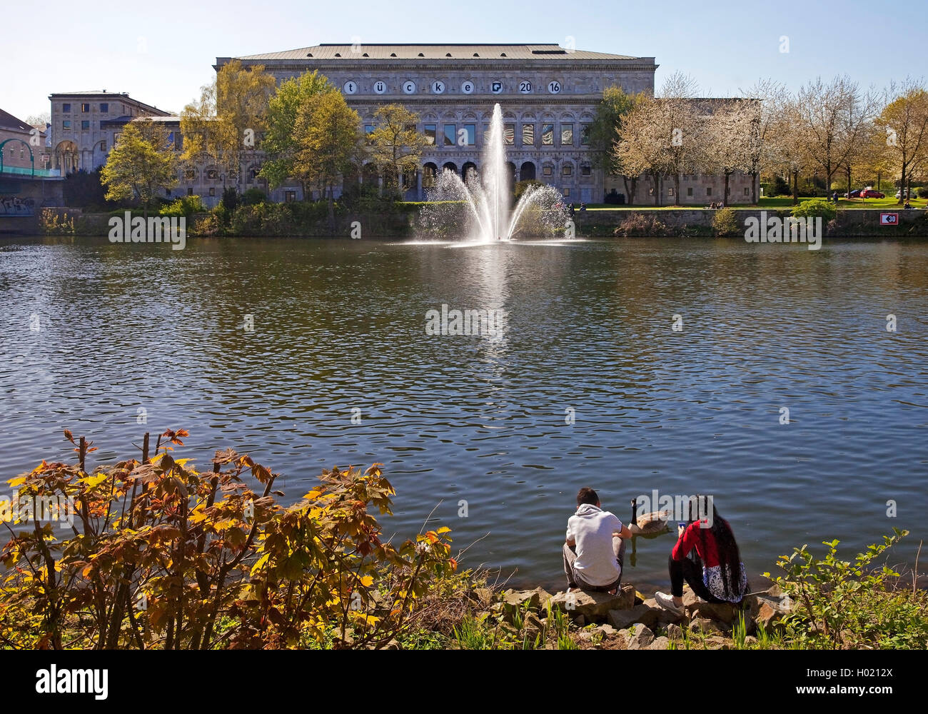 two teenagers at river Ruhr with municipal hall, Germany, North Rhine-Westphalia, Ruhr Area, Muelheim/Ruhr Stock Photo