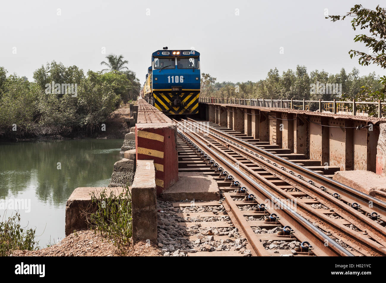 Operations for transporting and managing iron ore. Empty ore train from port crossing river bridge before travelling back to mine to pick up new load. Stock Photo