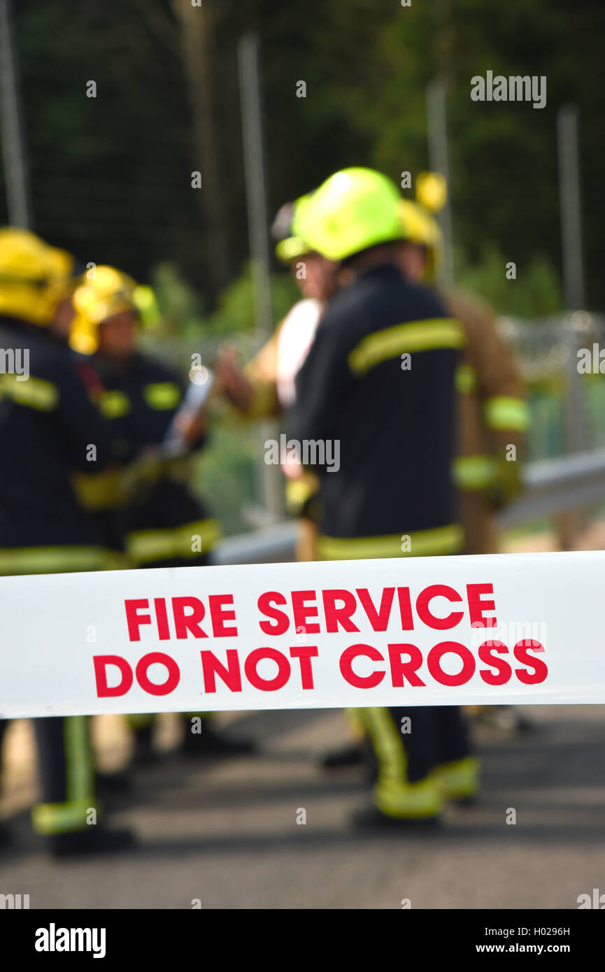 Firefighters at the scene of a major incident. Cordon tape and good depth with selective focus. Upright image. Stock Photo