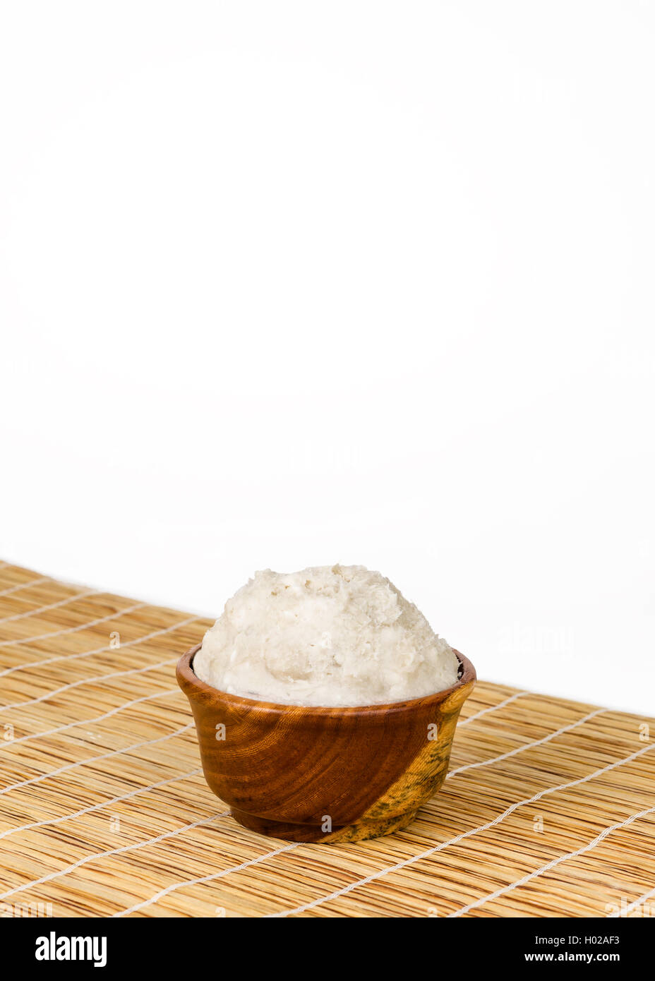 Unrefined, organic Shea butter in the wooden bowl  standing on the straw mat, clean white background. Stock Photo