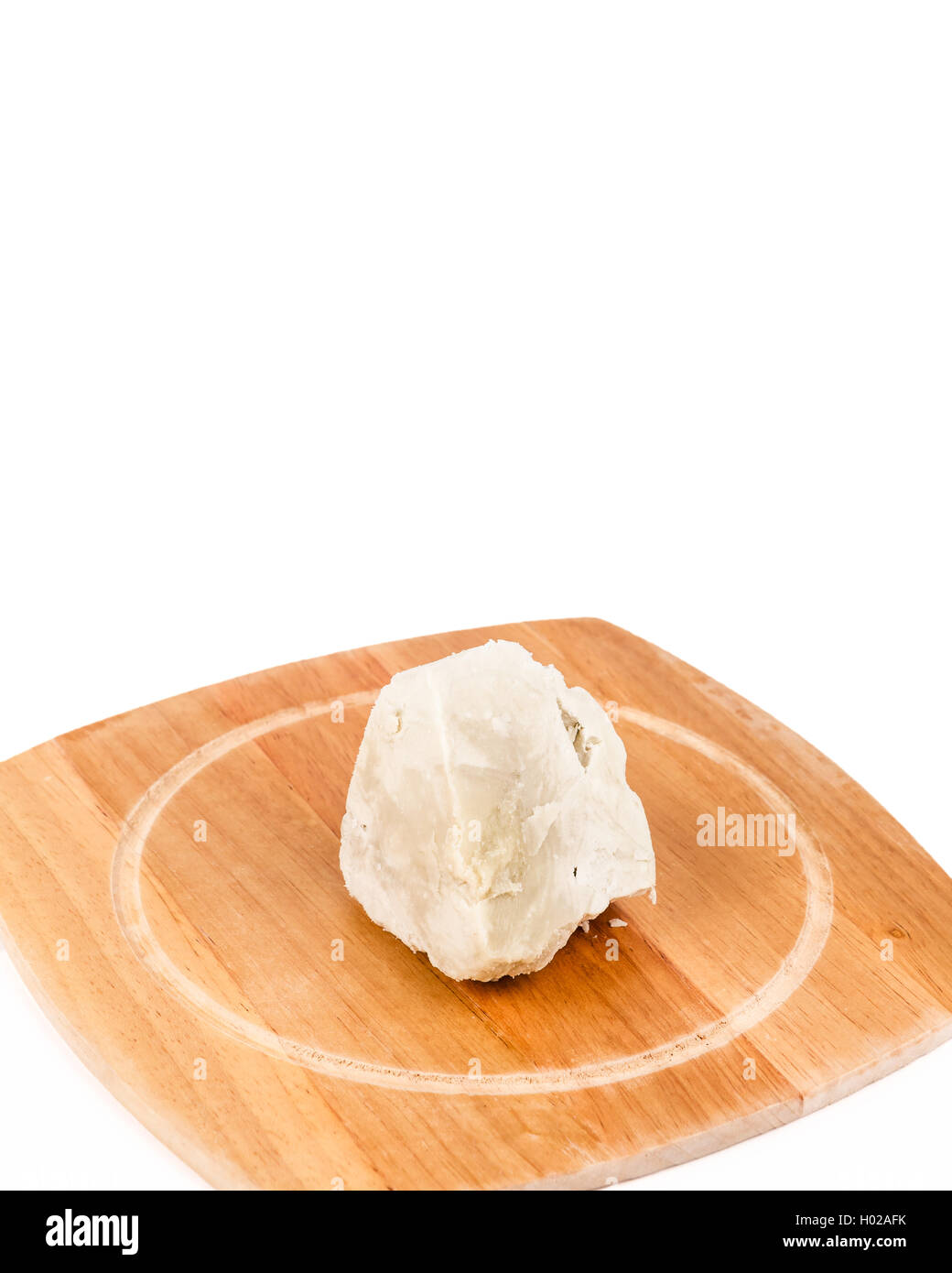 Unrefined, organic Shea butter laying on the wooden board standing on the clean white background. Stock Photo