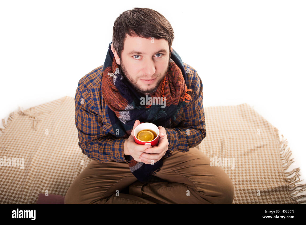 Portrait of a sick man with the flu coughing and holding a warm tea cup Stock Photo