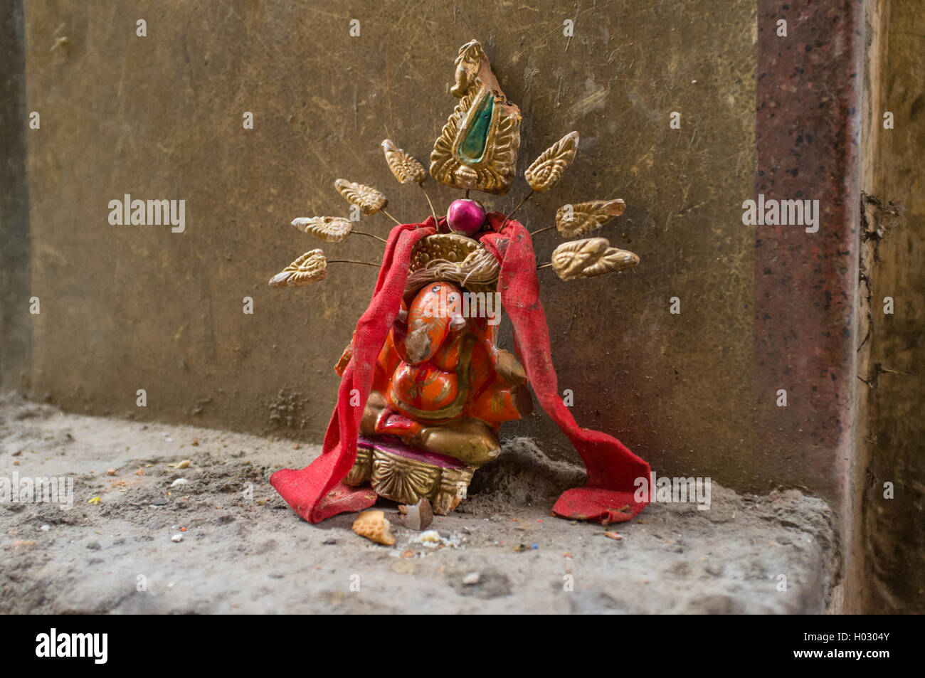 VARANASI, INDIA - 20 FEBRUARY 2015: Small Ganesh sculpture on wall in street. Ganesh is best-known and most worshipped deities i Stock Photo