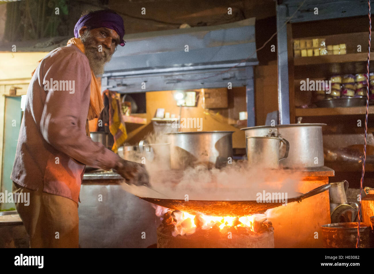 VARANASI, INDIA - 21 FEBRUARY 2015: Street vendor cooks meal in big pan on coal oven at night. Stock Photo