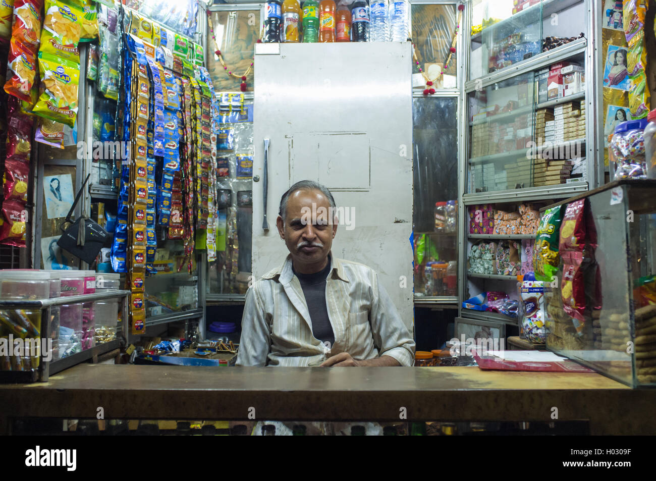 JODHPUR, INDIA - 11 FEBRUARY 2015: Indian vendor sits in shop with gutka hanging in background and other products. Gutka has mil Stock Photo