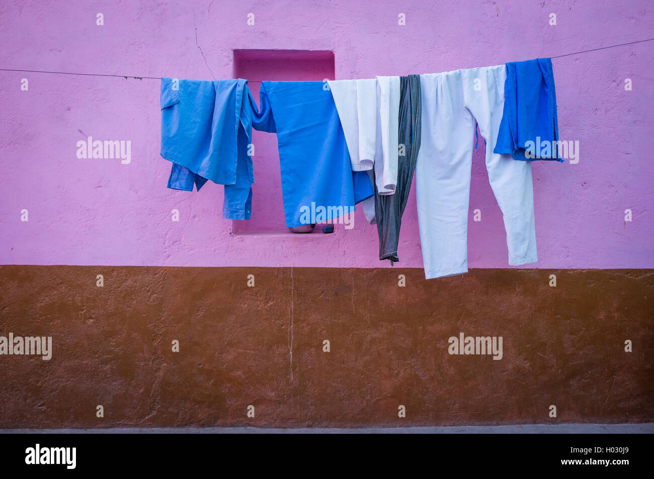 GODWAR REGION, INDIA - 12 FEBRUARY 2015: Clothes hang on wire next to pink and brown wall. Stock Photo