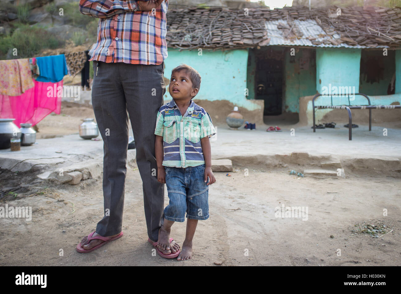 GODWAR, INDIA - 12 FEBRUARY 2015: Little boy stands next to father and looks towards him in family yard. Father not in view. Stock Photo