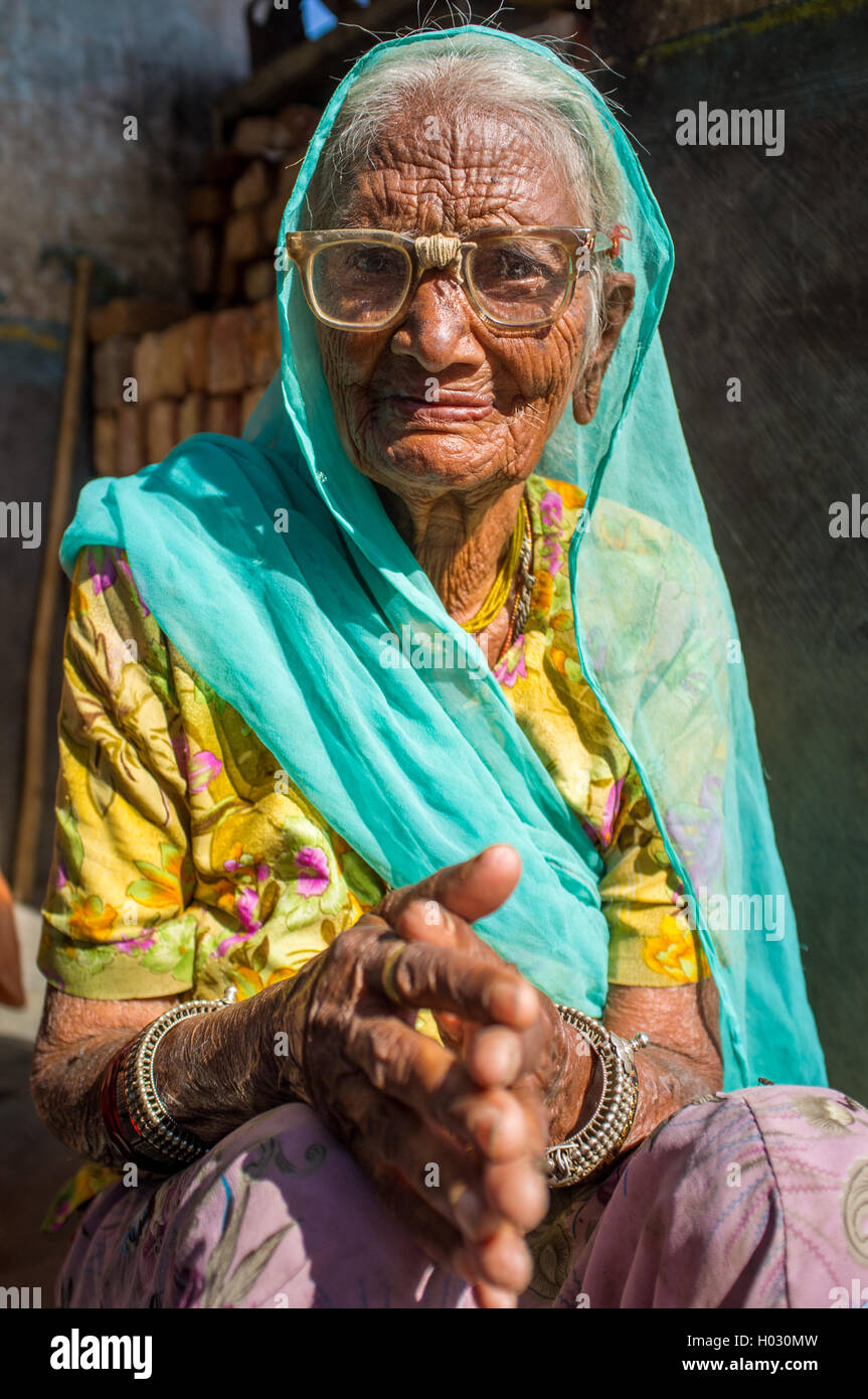 GODWAR REGION, INDIA - 13 FEBRUARY 2015: Elderly Indian woman in sari with covered head and repaired glasses sits in doorway of  Stock Photo