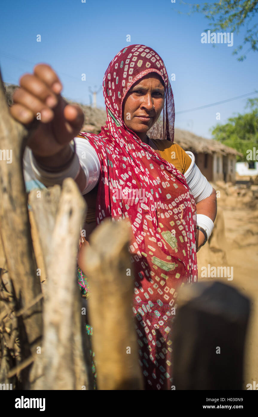 GODWAR REGION, INDIA - 13 FEBRUARY 2015: Rabari tribeswoman in sari decorated with traditional upper-arm bracelets holds gate of Stock Photo