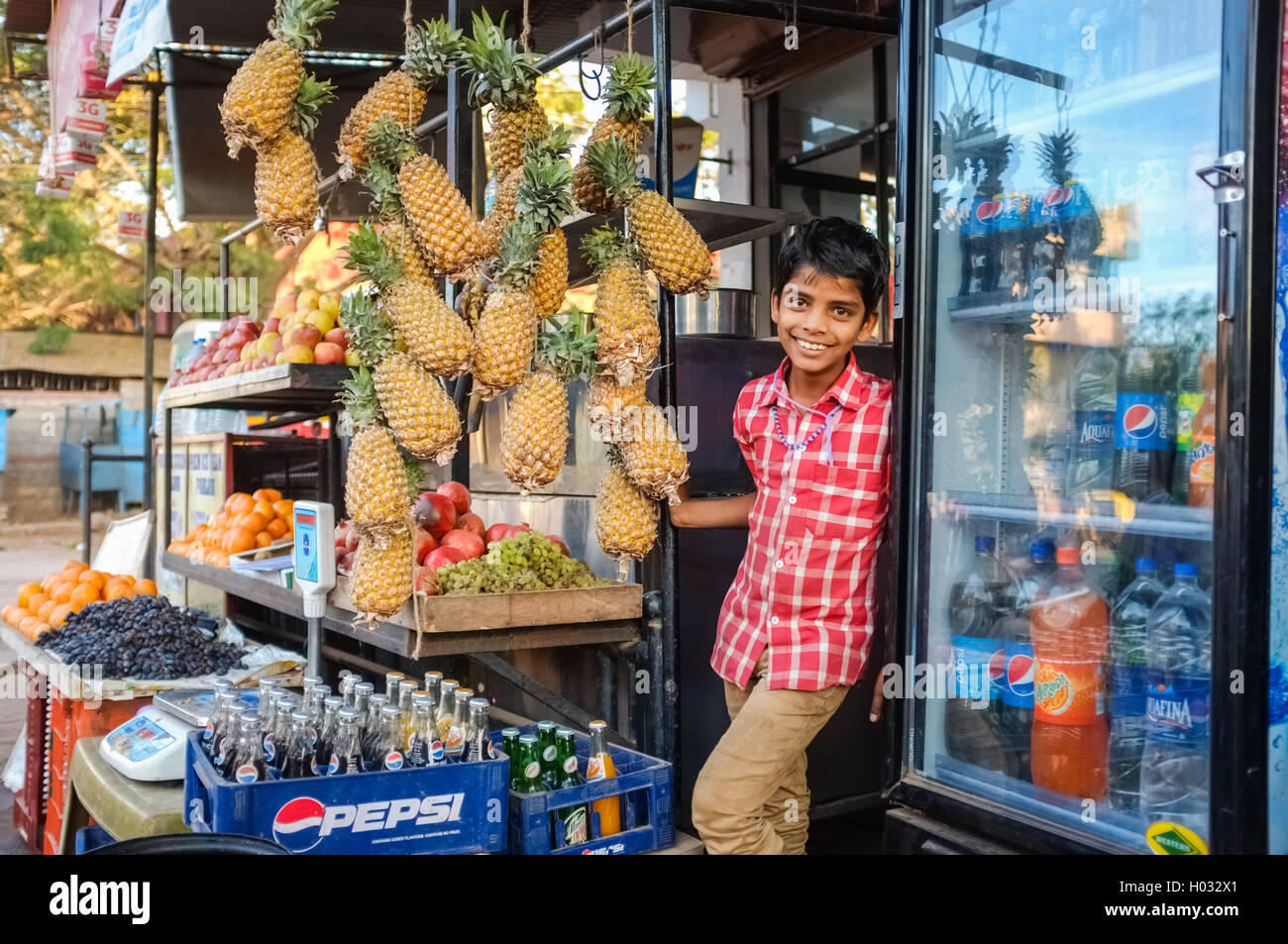 HOSPET, INDIA - 04 FEBRUARY 2015: Indian boy waiting with pineapples in front of store. Stock Photo