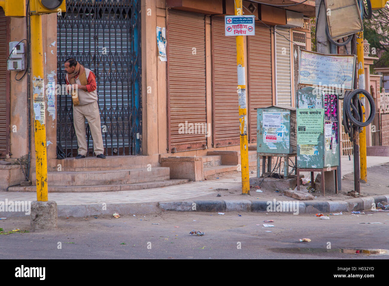 JODHPUR, INDIA - 12 FEBRUARY 2015: Man stands in doorway of building in empty street and looks around the corner. Stock Photo