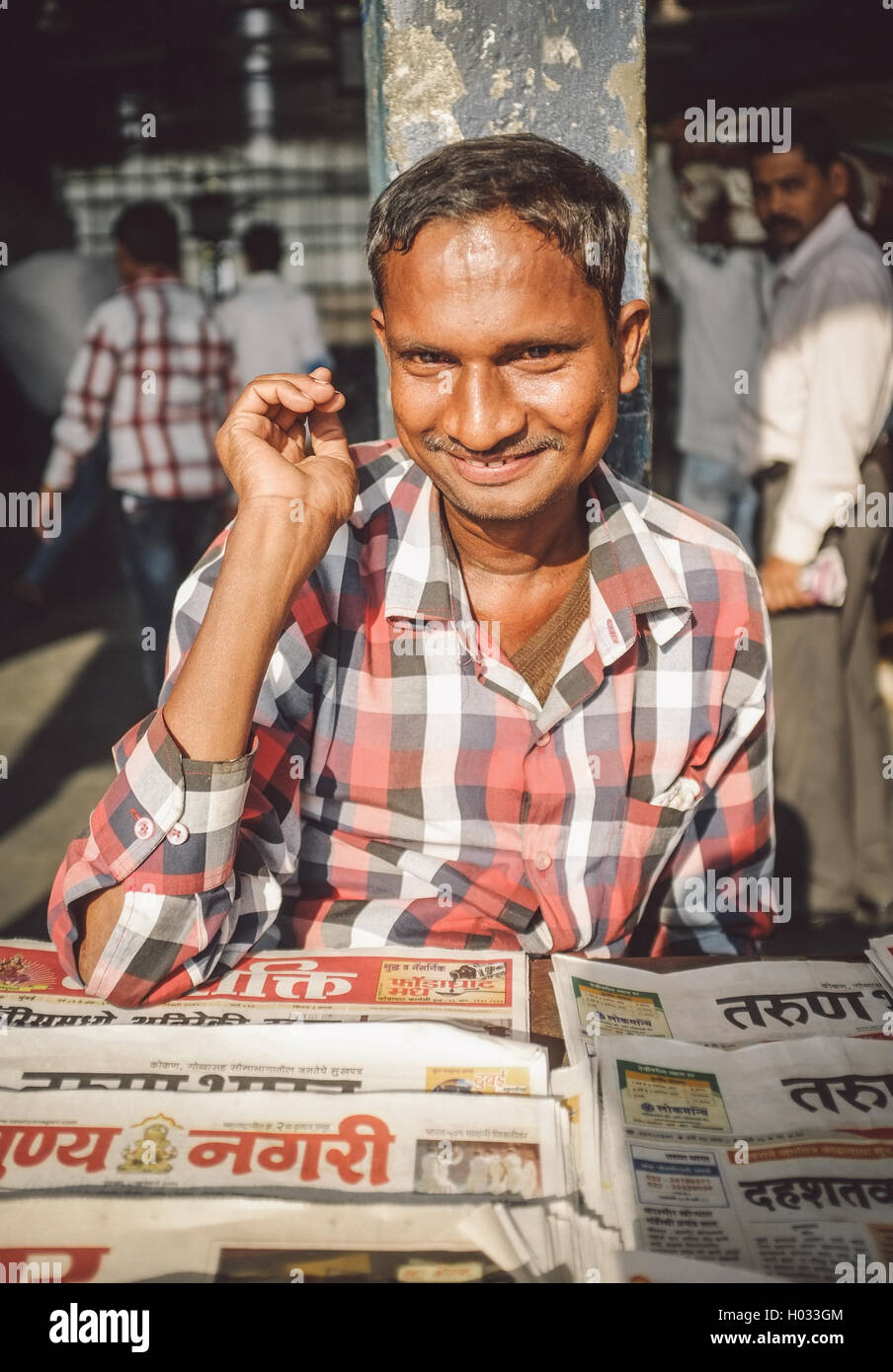 MUMBAI, INDIA - 08 JANUARY 2015: India man sells newspapers in front of train station. Post-processed with grain, texture and co Stock Photo